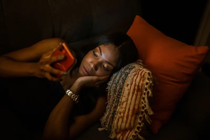 A woman on the couch at night, reading her phone